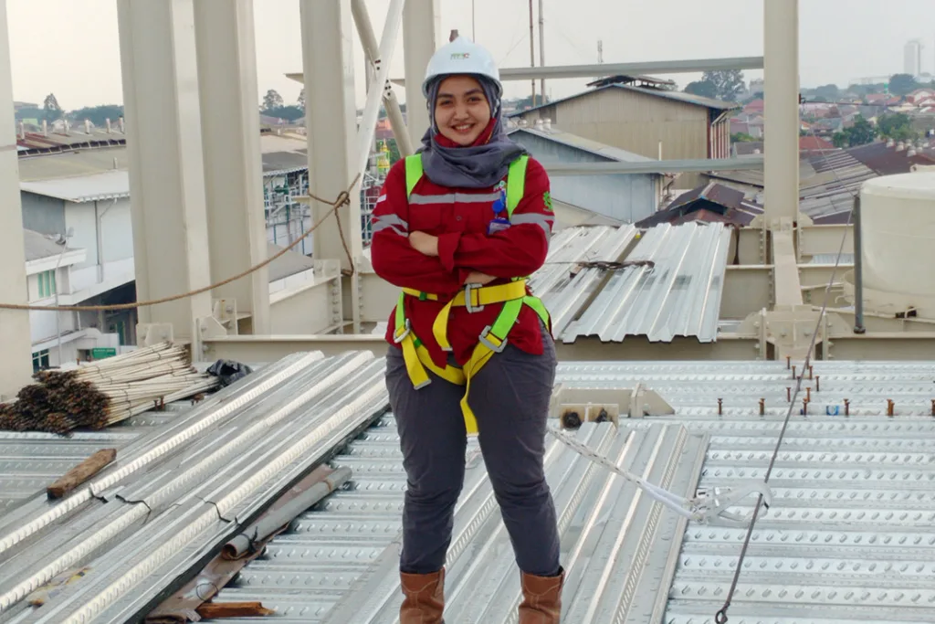 Sinar Alam Cakrabuana Woman Worker Standing in Project Facility Wearing Full Safety Tools